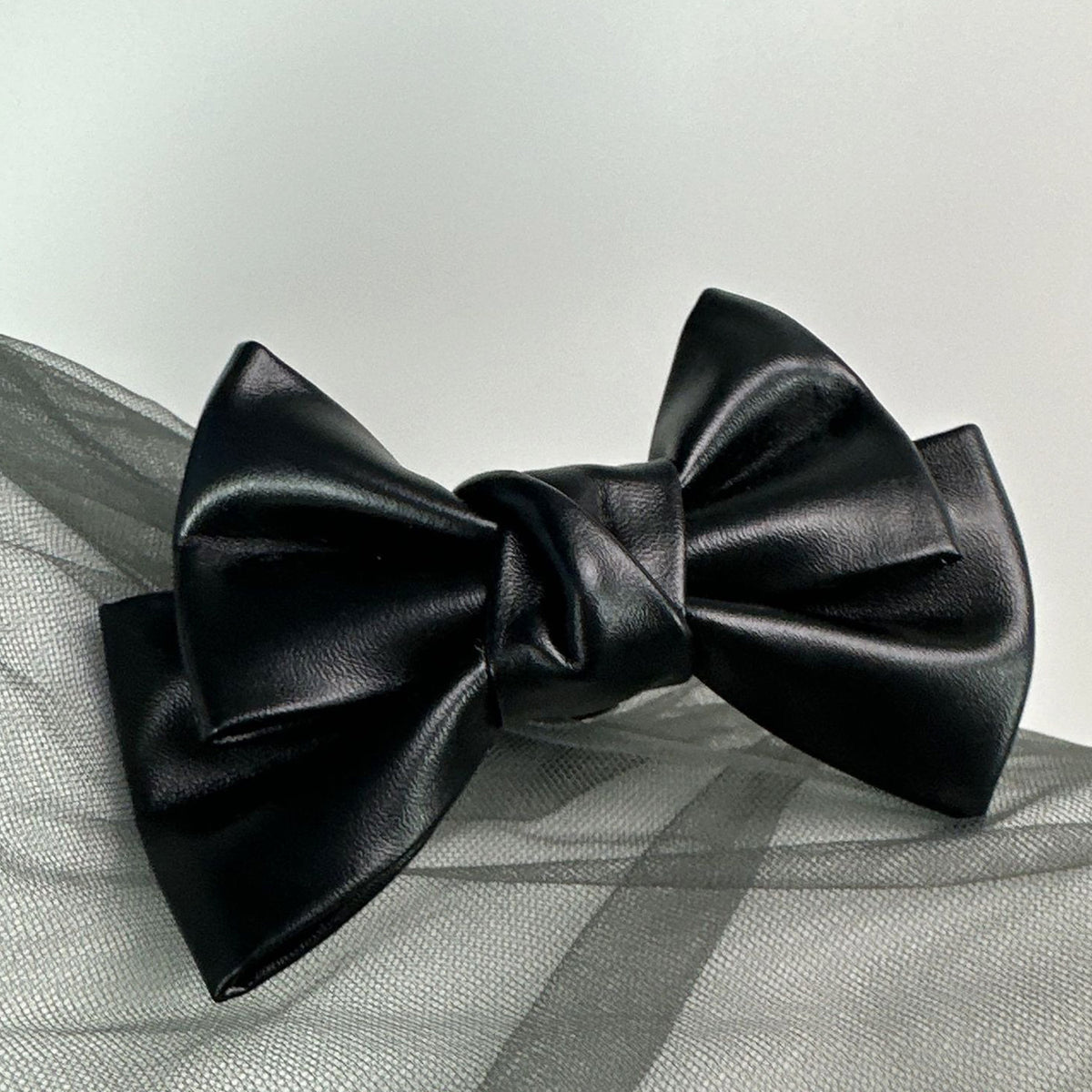 Front view of the Glossy Bow Anal Plug featuring a polished metal body and a black faux-leather ribbon, available on SexyMaker.