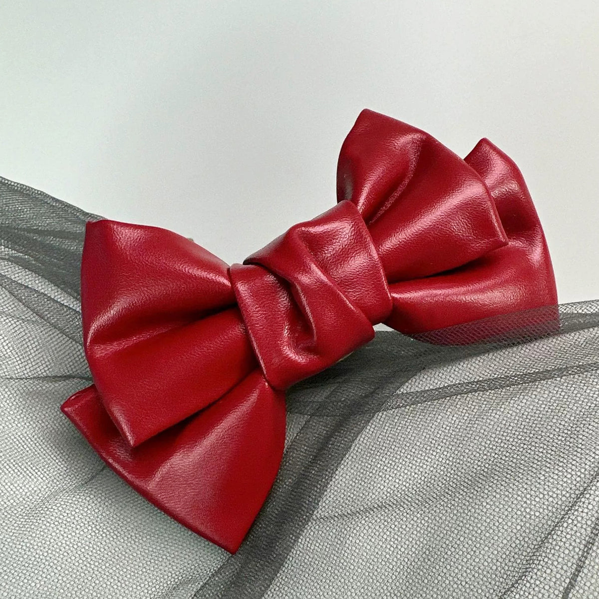 Front view of the Glossy Bow Anal Plug featuring a polished metal body and a black faux-leather ribbon, available on SexyMaker.