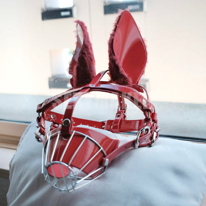 Close-up of glossy wet-look red human pup metal cage muzzle mask featuring feral fluffy faux fur ears and silver hardware for intense pet play by Sexy Maker.