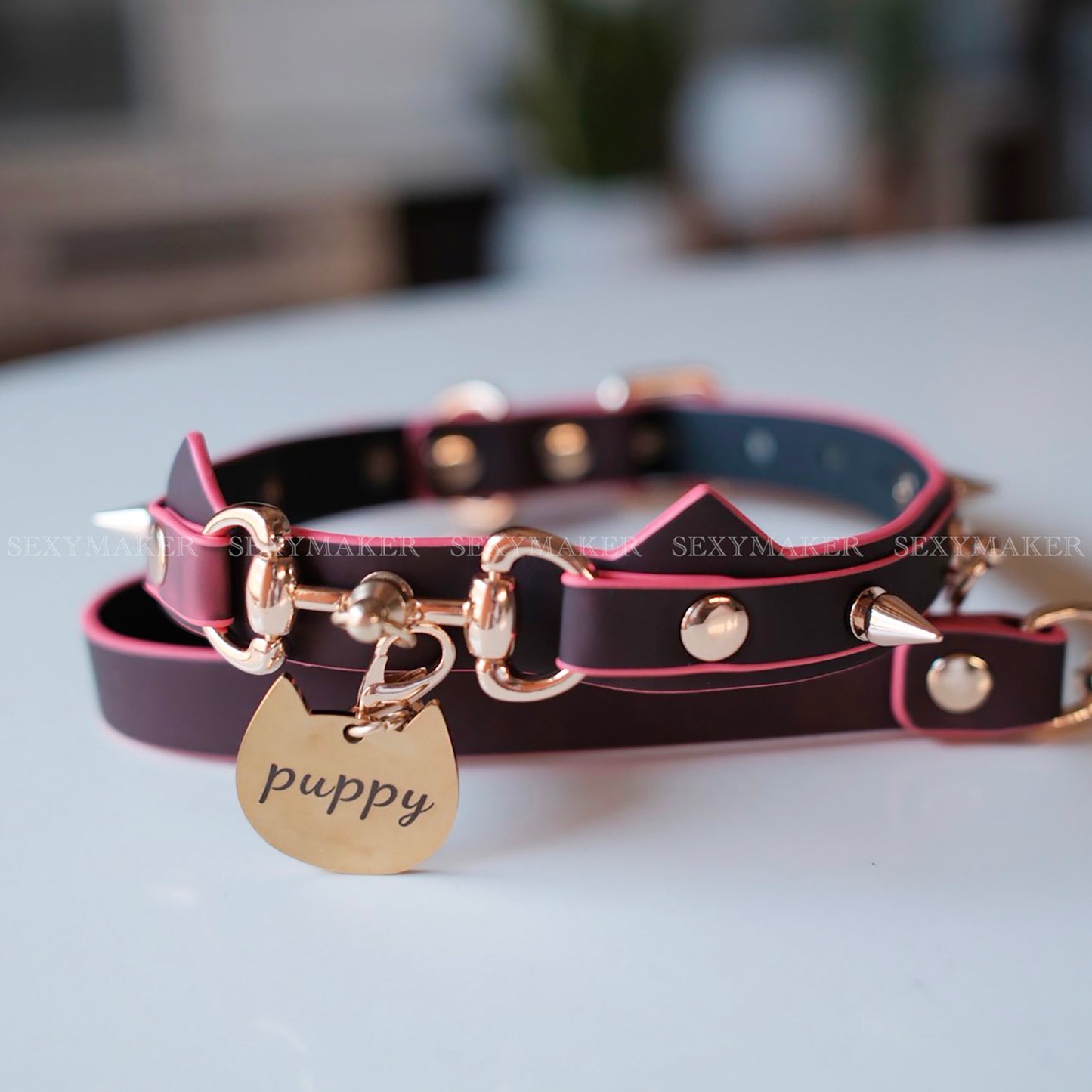 Close-up of heat-reactive color-changing black to red pet play collar featuring spiked cat ears and a gold puppy charm by Sexy Maker.