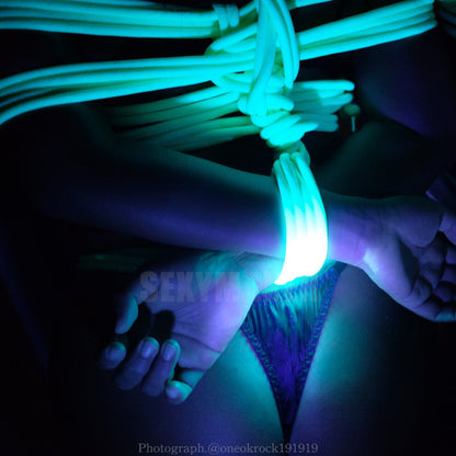 Close-up of neon green UV reactive Shibari bondage rope glowing brightly under blacklight for sensory rope play by Sexy Maker.