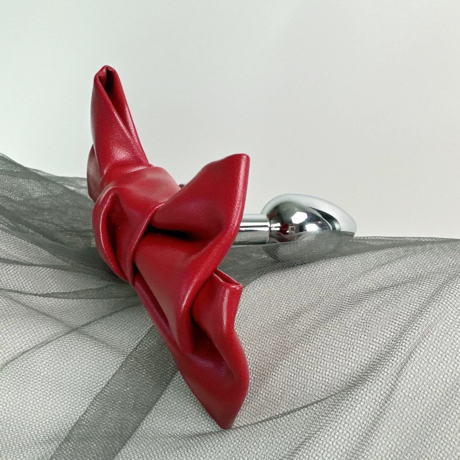 Front view of the Glossy Bow Anal Plug featuring a polished metal body and a black faux-leather ribbon, available on SexyMaker.