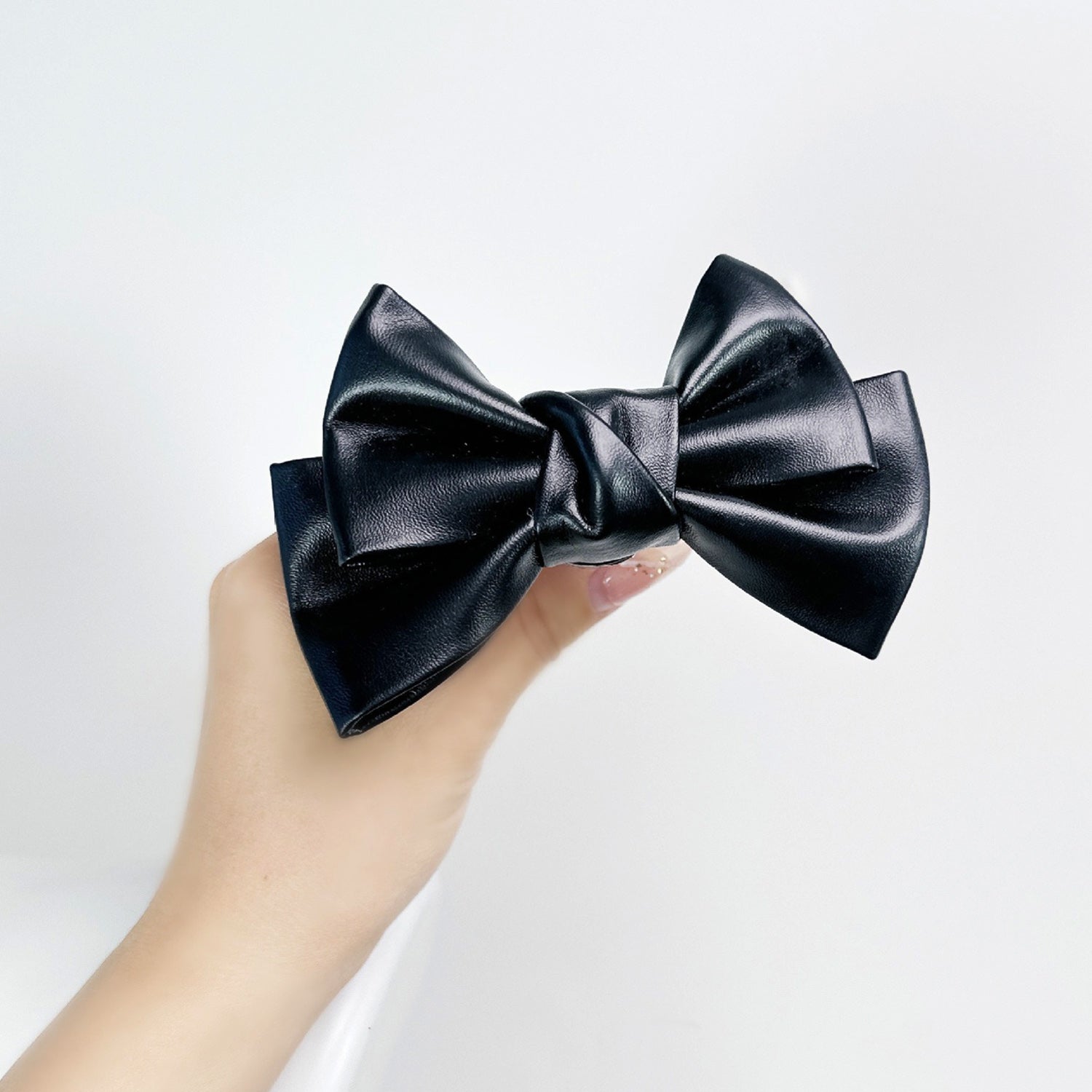 Front view of the Glossy Bow Anal Plug featuring a polished metal body and a black faux-leather ribbon, available on SexyMaker.