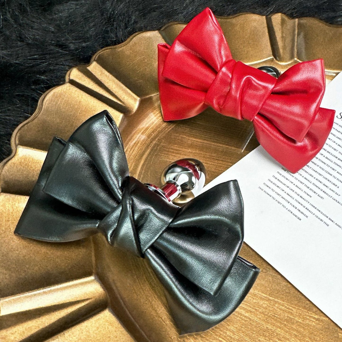 Front view of the Glossy Bow Anal Plug featuring a polished metal body and a black faux-leather ribbon, available on SexyMaker.