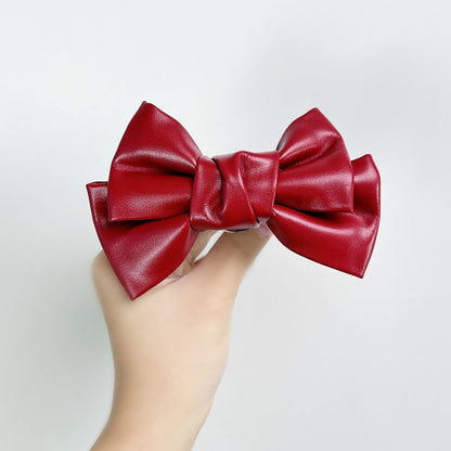 Front view of the Glossy Bow Anal Plug featuring a polished metal body and a black faux-leather ribbon, available on SexyMaker.