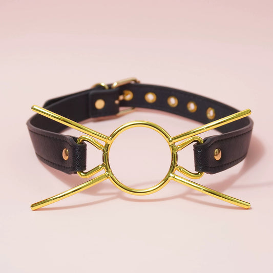 Close-up of golden metal cat whiskers O-ring gag with black adjustable vegan leather straps for kitten pet play by Sexy Maker.